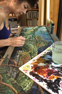 Kathleen Mazzotta applies paint to alligator table